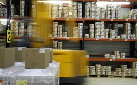 Forklift moving in a warehouse with large shelves of packages