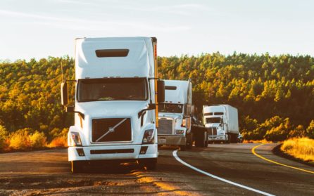 three white trucks along the side of the road